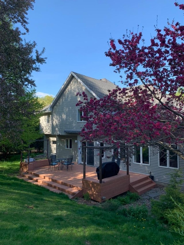 rear view of house featuring a lawn and a wooden deck