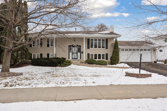 split foyer home with driveway, a chimney, and an attached garage