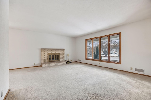 unfurnished living room with baseboards, carpet, visible vents, and a brick fireplace