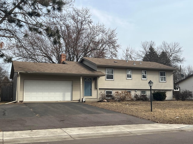 tri-level home with a garage, a chimney, and driveway