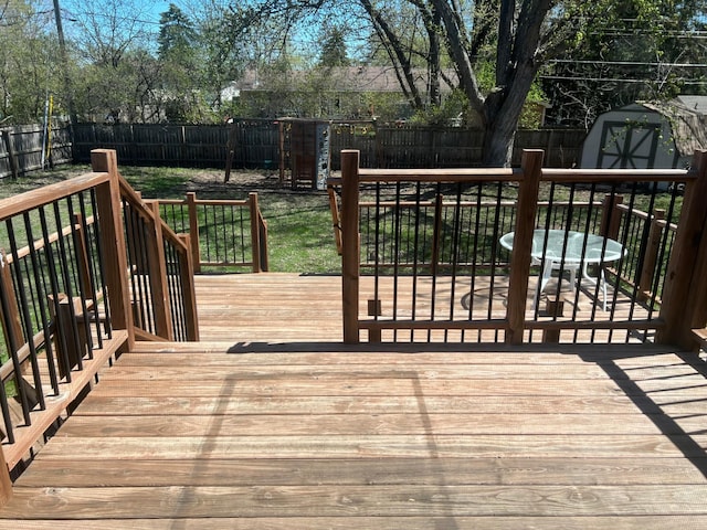 wooden deck featuring a storage shed, a lawn, an outbuilding, and a fenced backyard