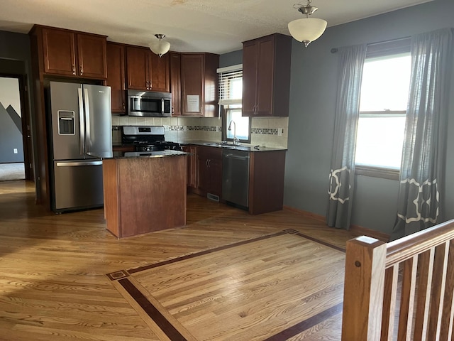 kitchen with decorative backsplash, a kitchen island, dark countertops, hanging light fixtures, and stainless steel appliances