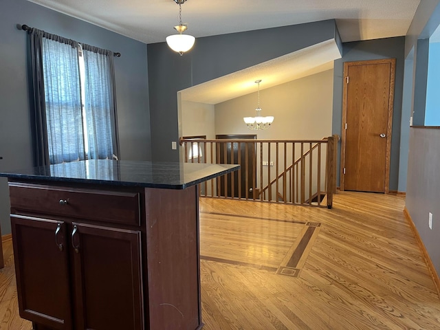 kitchen with light wood-type flooring, dark brown cabinetry, a notable chandelier, and decorative light fixtures