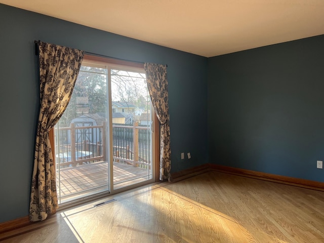empty room with baseboards, visible vents, and wood finished floors