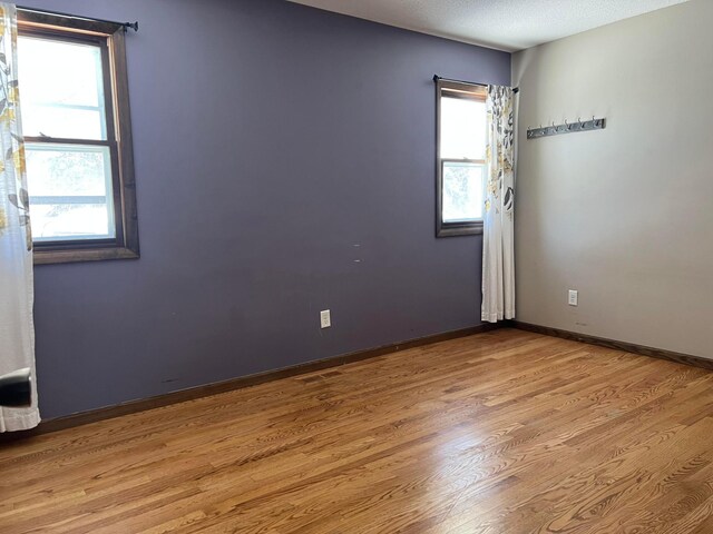 unfurnished room with baseboards, a textured ceiling, and wood finished floors