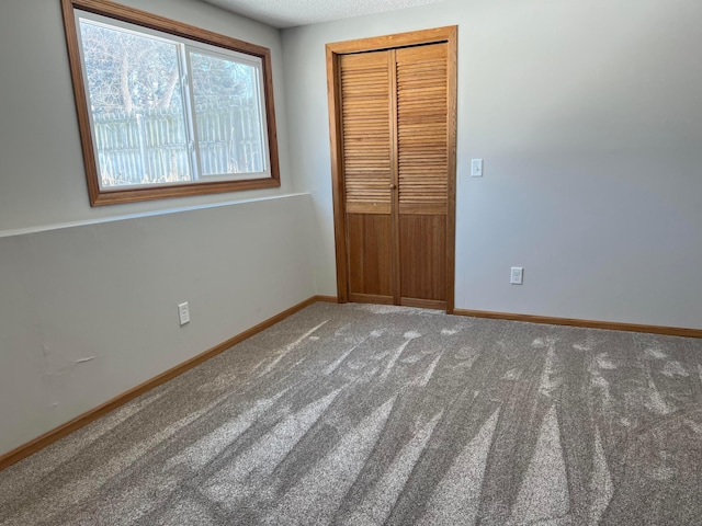 unfurnished bedroom with carpet flooring, baseboards, and a closet