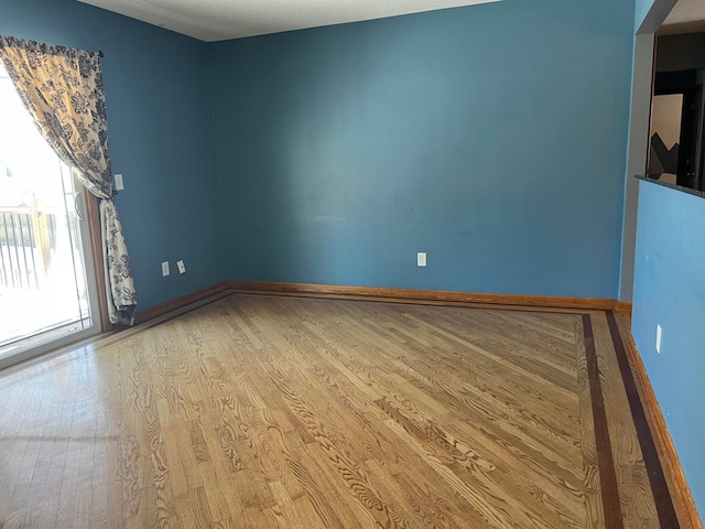 empty room with baseboards and wood finished floors