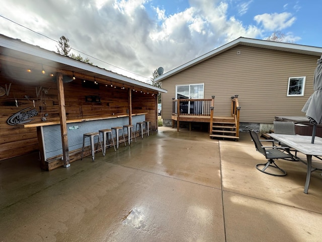 view of patio / terrace featuring outdoor dry bar, outdoor dining space, and a wooden deck