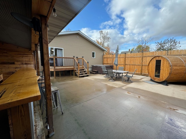 view of patio featuring a hot tub, a deck, and a fenced backyard