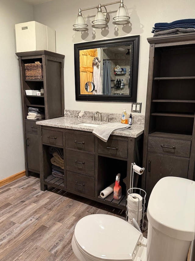 full bath featuring baseboards, vanity, toilet, and wood finished floors