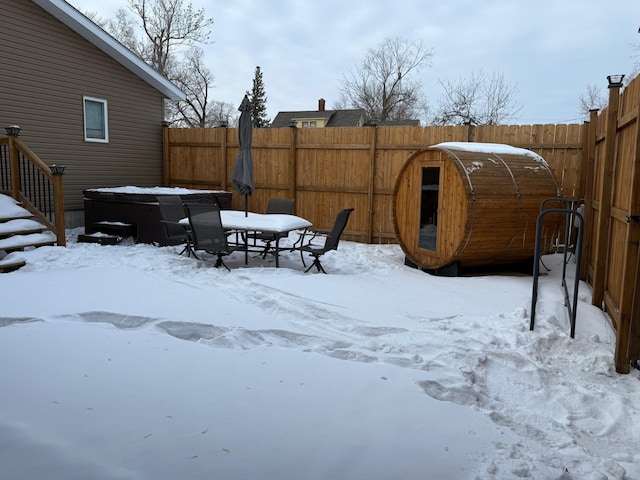 snowy yard featuring a fenced backyard and a hot tub