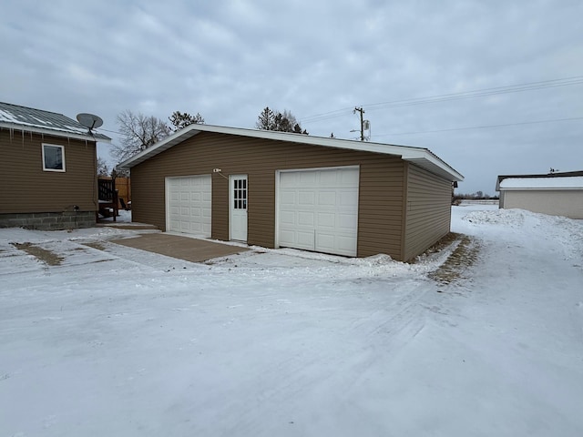 snow covered garage featuring a garage