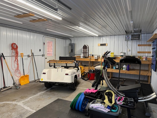 garage with a workshop area, metal wall, and electric panel