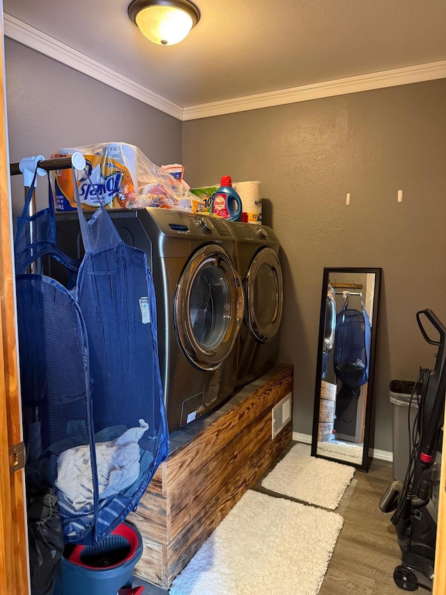 laundry area featuring laundry area, baseboards, washer and clothes dryer, wood finished floors, and crown molding