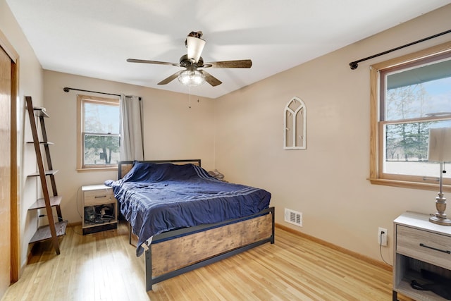 bedroom with ceiling fan, light wood-type flooring, visible vents, and baseboards