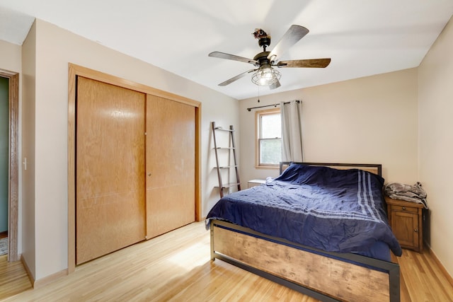 bedroom with ceiling fan, a closet, baseboards, and light wood-style floors