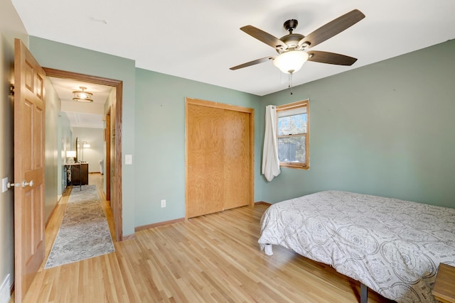 bedroom featuring ceiling fan, a closet, baseboards, and wood finished floors