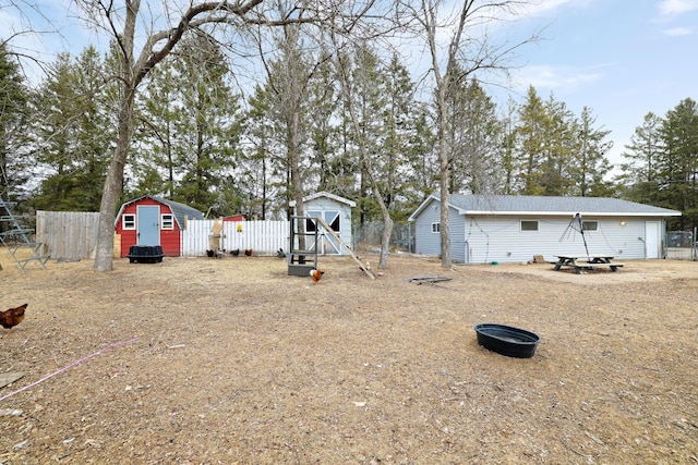 view of yard featuring an outbuilding, a storage unit, and fence