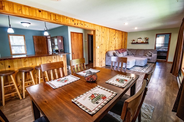 dining room with dark wood finished floors and wooden walls