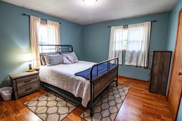 bedroom with multiple windows and wood finished floors