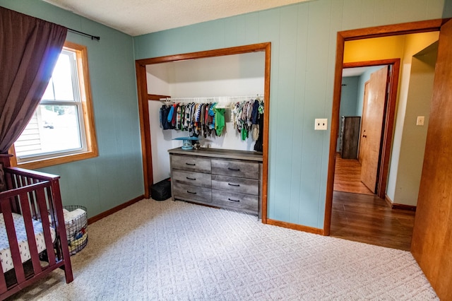 bedroom with a closet, light colored carpet, and baseboards