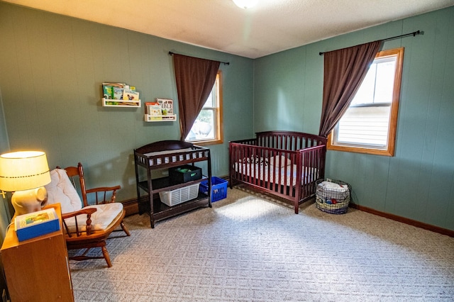 bedroom with a nursery area, carpet floors, and baseboards