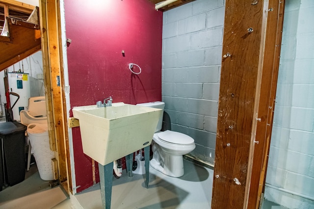 half bath featuring concrete block wall, water heater, a sink, and toilet