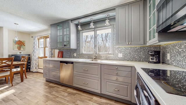 kitchen featuring light countertops, appliances with stainless steel finishes, glass insert cabinets, and gray cabinetry