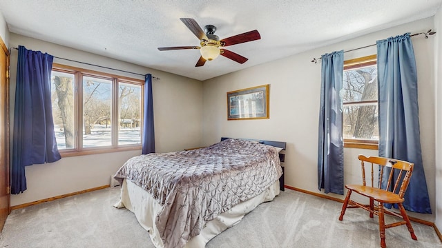 bedroom with light carpet, ceiling fan, baseboards, and a textured ceiling