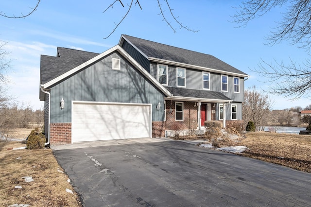 view of front of home featuring driveway, roof with shingles, a garage, and brick siding