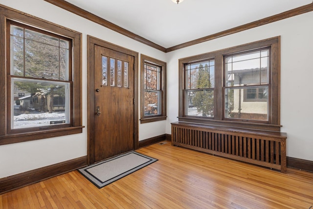 entrance foyer featuring radiator, light wood-style floors, baseboards, and ornamental molding