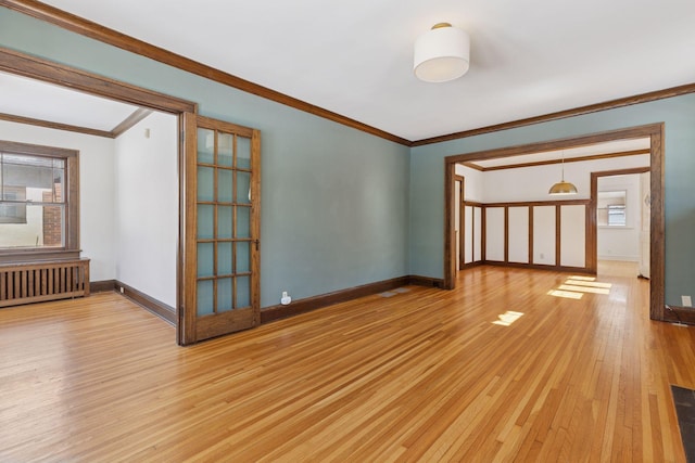 unfurnished room with ornamental molding, radiator, baseboards, and light wood finished floors