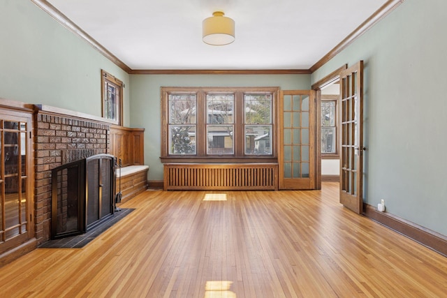 unfurnished living room featuring light wood-style floors, radiator, a fireplace, and baseboards