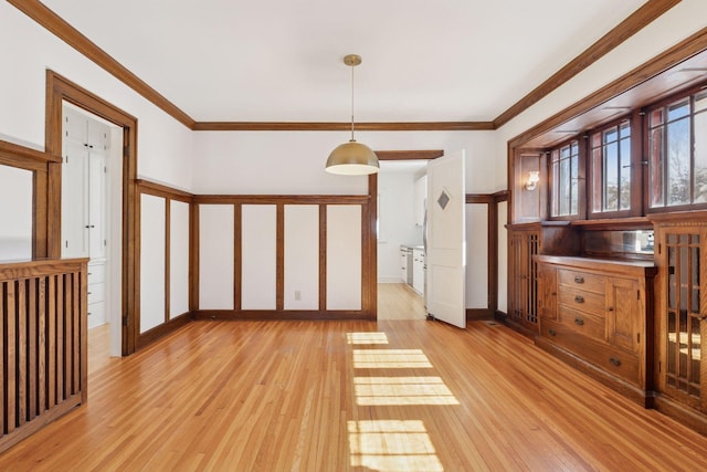 unfurnished room with light wood-style floors, crown molding, and baseboards