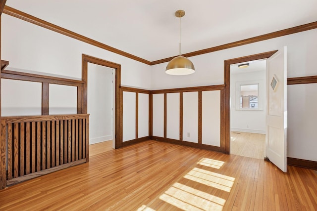 empty room featuring light wood-style floors, ornamental molding, and baseboards