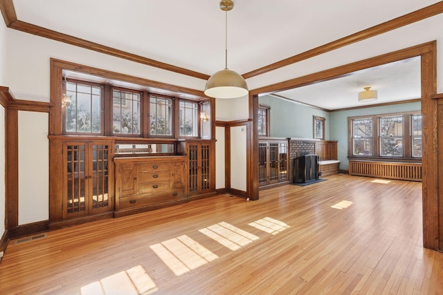 unfurnished living room featuring ornamental molding, radiator, visible vents, and hardwood / wood-style floors