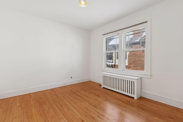 unfurnished room with radiator, baseboards, and hardwood / wood-style floors