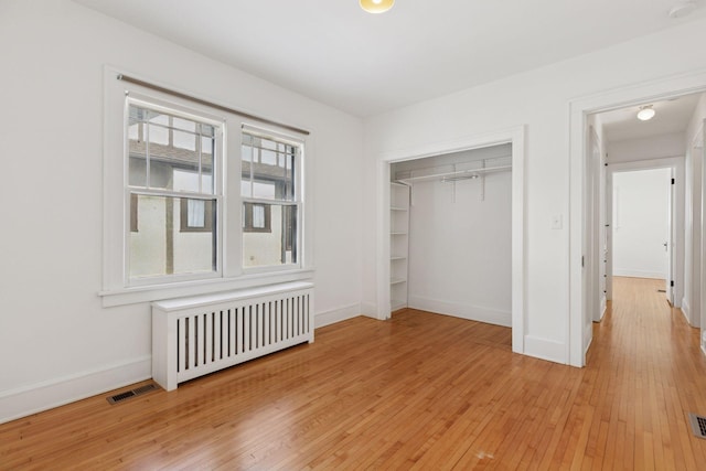 unfurnished bedroom with radiator, visible vents, baseboards, and light wood finished floors