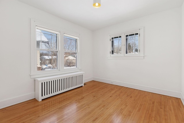 unfurnished room featuring radiator, baseboards, and hardwood / wood-style flooring