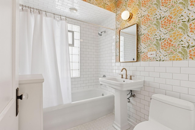 full bath with tile walls, shower / bath combination with curtain, toilet, wainscoting, and wallpapered walls