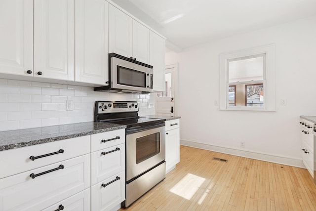 kitchen with light wood finished floors, visible vents, decorative backsplash, appliances with stainless steel finishes, and white cabinetry