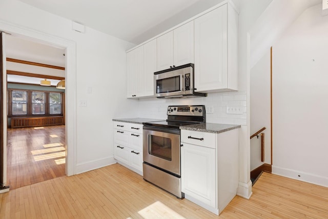 kitchen featuring stainless steel appliances, white cabinetry, decorative backsplash, radiator, and light wood finished floors