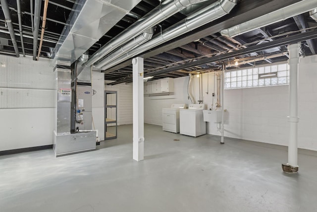 basement featuring heating unit, washing machine and dryer, and a sink