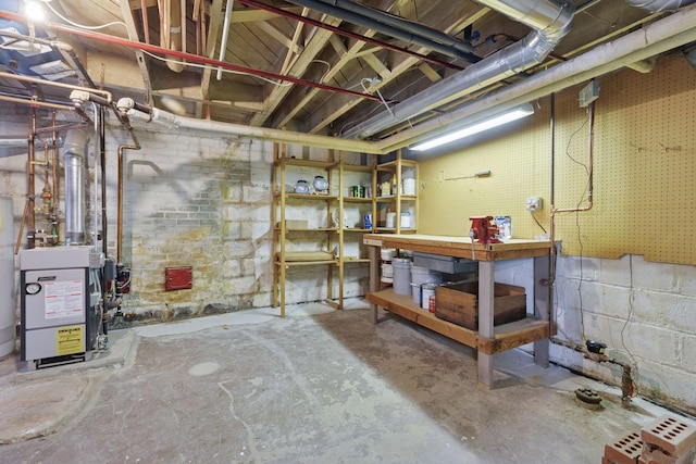 unfinished basement with a workshop area, a heating unit, and concrete block wall