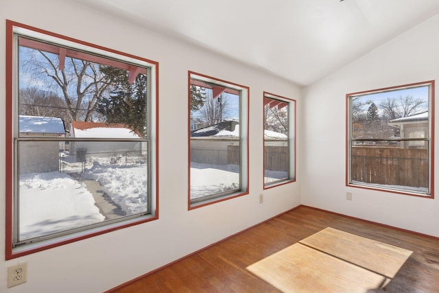 spare room featuring plenty of natural light, vaulted ceiling, and wood finished floors