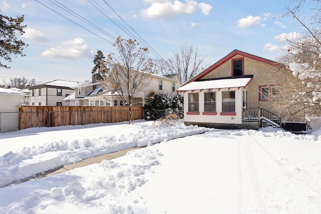 snow covered rear of property featuring fence