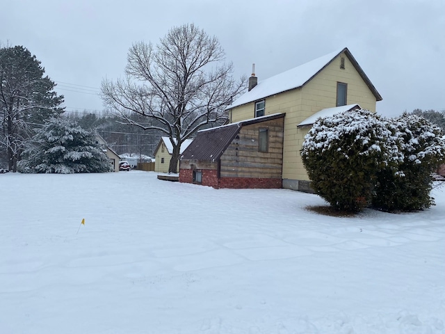 view of snowy exterior with a chimney