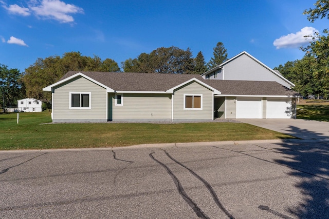 view of front facade with driveway, an attached garage, a front lawn, and roof with shingles