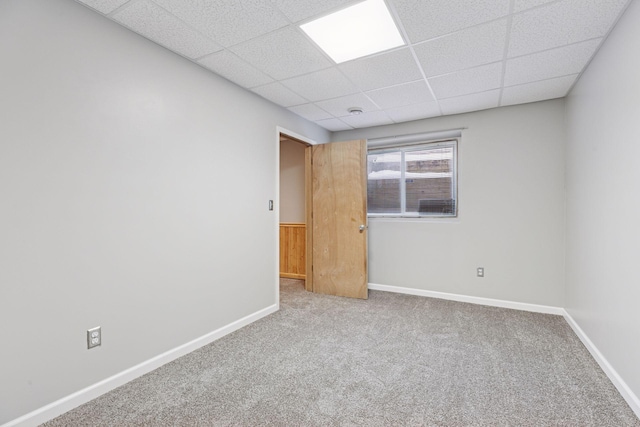 carpeted empty room with a paneled ceiling and baseboards