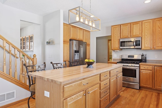 kitchen with wood counters, visible vents, light wood finished floors, and stainless steel appliances